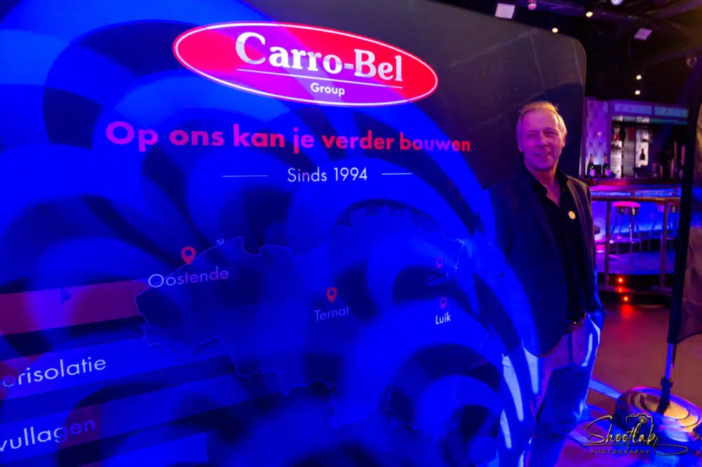 Jimmy De Breucker bij een Carro-Bel-stand met kaart van België, onderdeel van het verhaal van Jimmy De Breucker